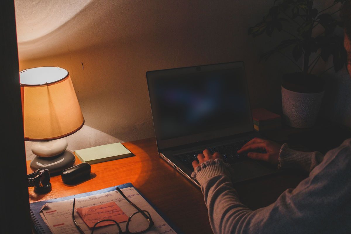 A laptop open on a kitchen table late at night