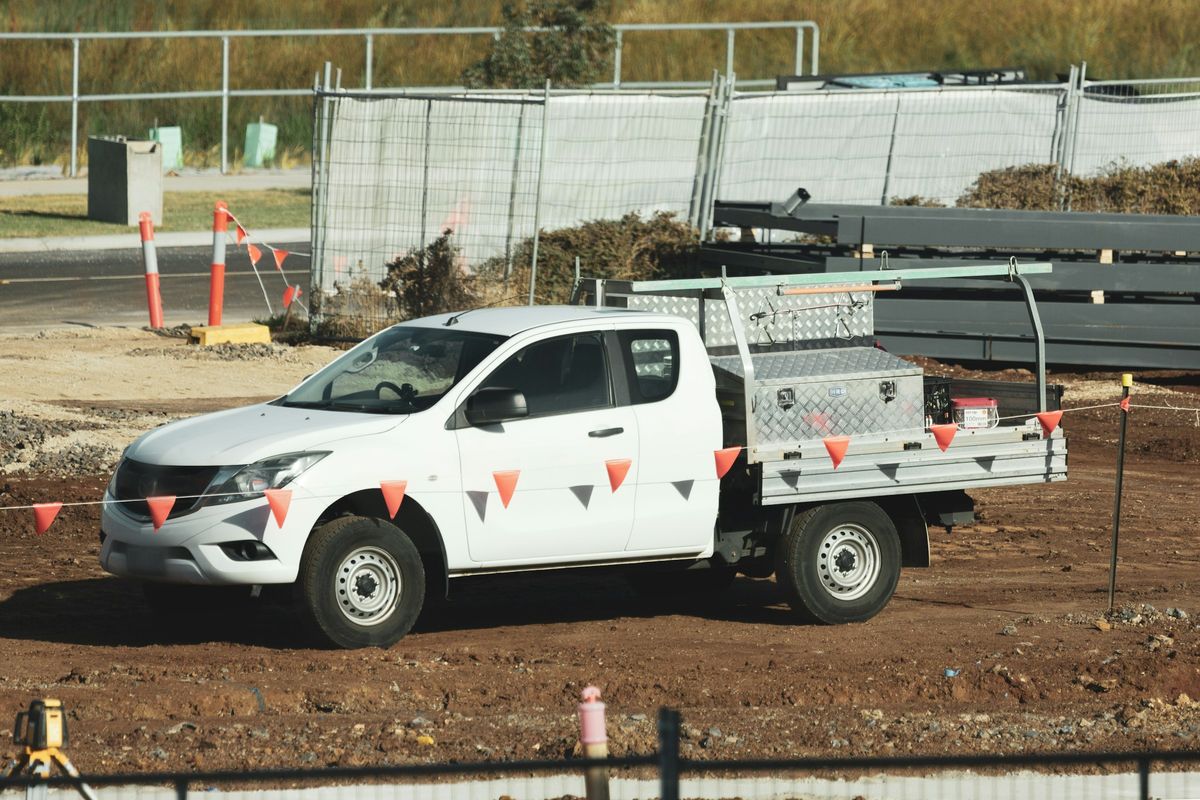 A tray-back ute with a toolbox parked on a building site.